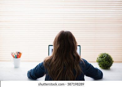 Rear View Of Hipster Businesswoman Using Laptop At Her Desk