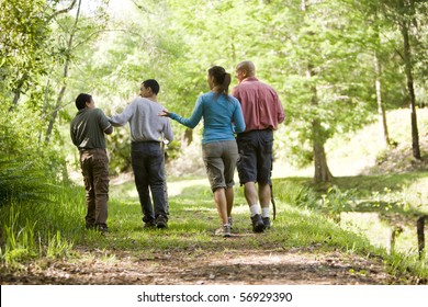 Rear View Of Hispanic Family Walking Along Trail In Park, Boys 10 And 14 Years Old