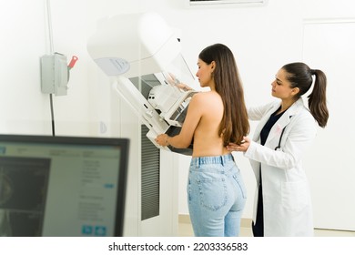 Rear view of an hispanic young woman getting a mammogram to check for breast cancer with the help of a female doctor at the imaging diagnostic center