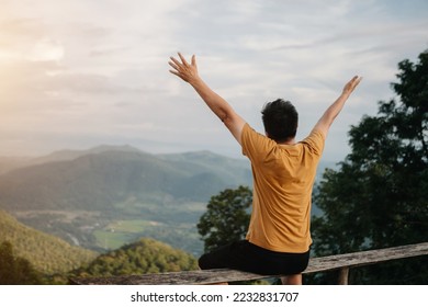 Rear view image of a male traveler sitting and looking at a beautiful mountain,flower field and nature view in sin light - Powered by Shutterstock