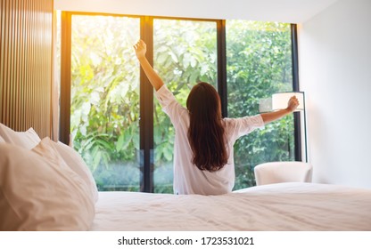 Rear View Image Of A Woman Do Stretching After Waking Up In The Morning  , Looking At A Beautiful Nature View Outside Bedroom Window 