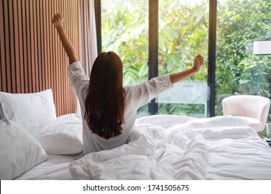 Rear View Image Of A Woman Do Stretching After Waking Up In The Morning  , Looking At A Beautiful Nature View Outside Bedroom Window 