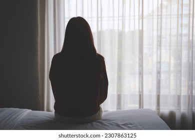 Rear view image of a woman sitting alone on a bed in bedroom - Powered by Shutterstock