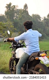 Rear view of an indian young man riding a motorcycle near a paddy field. Location: Kerala, India, Date 02-02-2022 - Shutterstock ID 2184051415