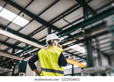 A Rear View Of An Industrial Woman Engineer With Smartphone In A Factory, Working.