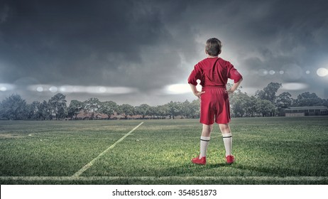 Rear View Of Kid Boy In Red Uniform On Soccer Field