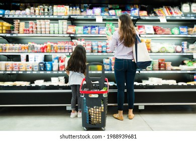 Rear View Of A Latin Family Looking And Choosing Dairy Products At The Supermarket During A Quick Shopping Trip To The Store