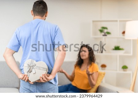 Rear view of a latin man giving chocolates to a woman to apologize at home
