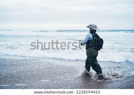 rear view of a latin woman fishing on the shore of the beach of the Pacific Ocean