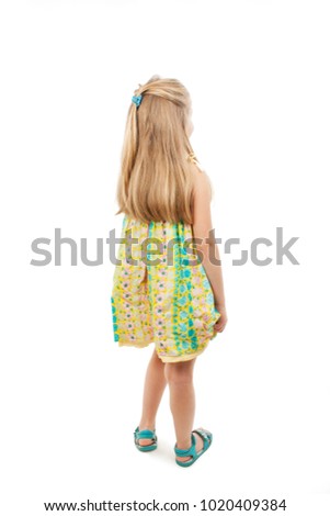 Rear view of little girl in floral dress looking at wall. Isolated on white background