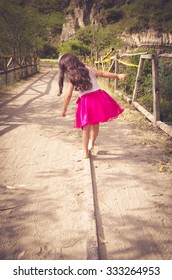 Rear View Of Little Girl In Pink Dress Walking On A Wooden Beam