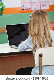 Rear View Of Little Girl Using Laptop In Preschool