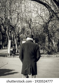 Rear View Of A Lonely Old Man With A Hat Walking In The Park. Vintage Black And White Photography.