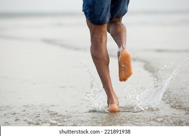 Rear View Low Angle View Of A Man Running Barefoot In Water