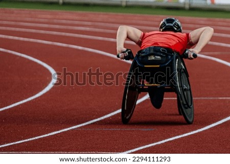 rear view male athlete in racing wheelchair riding on red track stadium, summer para athletics championships