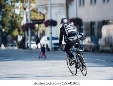 A rear view of male bicycle courier delivering packages in city. Copy space.