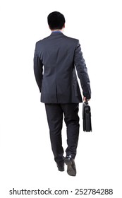 Rear View Of Male Businessperson Walking In The Studio While Carrying Briefcase