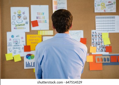 Rear view of male executive looking at the bulletin board in office - Powered by Shutterstock