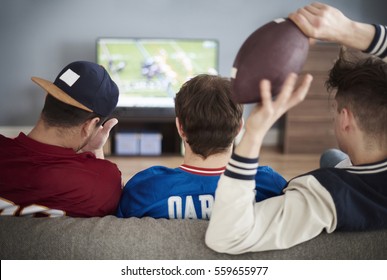 Rear view of male friends and tv on the background