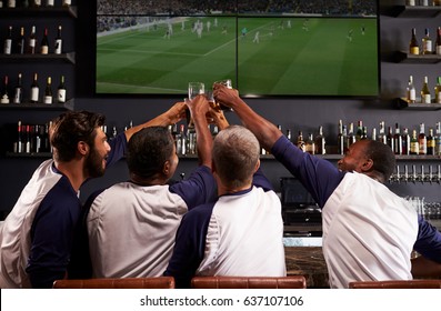 Rear View Of Male Friends Watching Game In Sports Bar