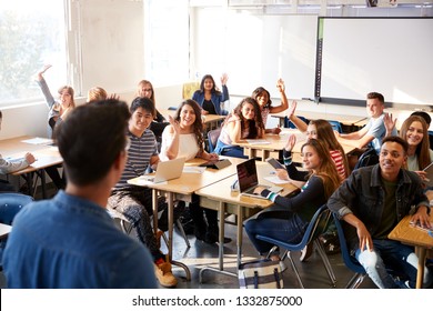 Rear View Of Male High School Teacher Standing At Front Of Class Teaching Lesson