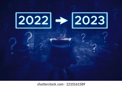Rear view of male manager relaxing on the chair while looking at 2022 change be 2023 number with question mark symbol - Shutterstock ID 2210161589