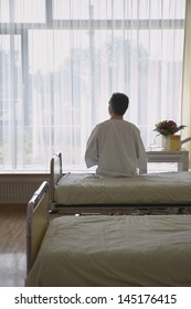 Rear View Of A Male Patient Sitting In Hospital Bed