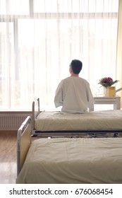 Rear View Of A Male Patient Sitting In Hospital Bed