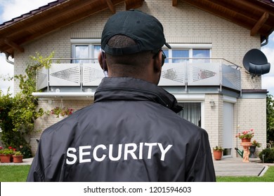 Rear View Of A Male Security Guard In Front Of House