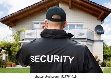 Rear View Of Male Security Guard Standing Outside The House Wearing Black Jacket