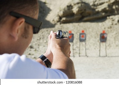 Rear view of man aiming target with gun