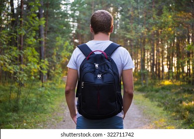 Rear View Of Man With Backpack Hiking In Forest