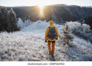 Rear view of man with backpack on hiking trip, solo trekking in the mountains, hiking with backpack in nature in winter season. High quality photo - Powered by Shutterstock