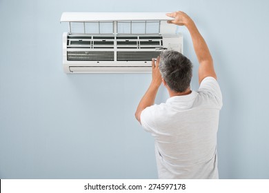 Rear View Of A Man Cleaning Air Conditioning System
