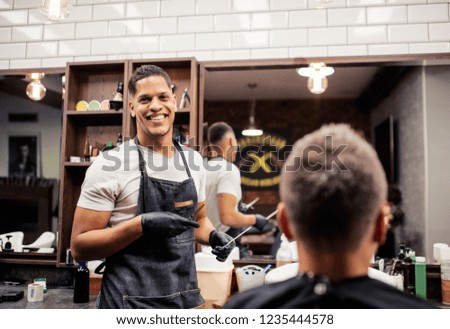 Rear view of man client visiting haidresser and hairstylist in barber shop.