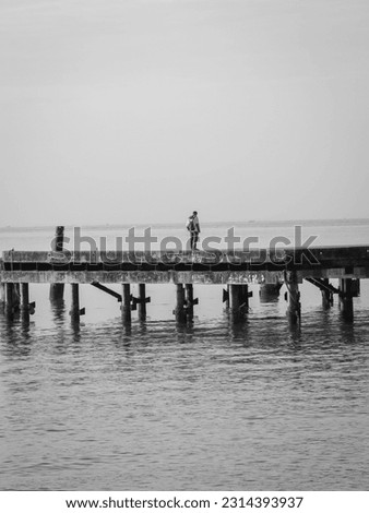 rear view of a man fishing on old concrete jetty in hazy morning
