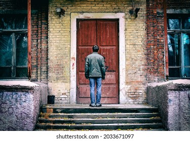 Rückansicht eines Mannes vor dem alten Haus vor der geschlossenen Tür