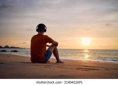 Rear view of man with headphones on beach. Serenity, contemplation and listening music at beautiful sunset.
 - Powered by Shutterstock