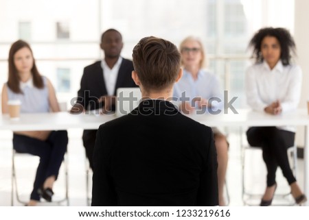 Rear view at man job seeker applicant during performance at interview with hr team, male vacancy candidate sits back talking making first impression on recruiters, human resources, employment concept