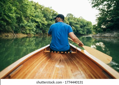 Rear View Of Man Paddling Canoe In The Forest Lake