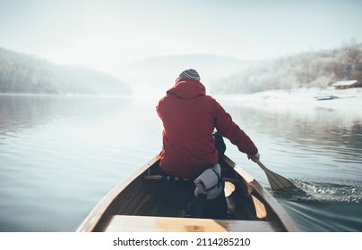 Rear View Of Man Paddling Canoe On The Winter Sunny Day