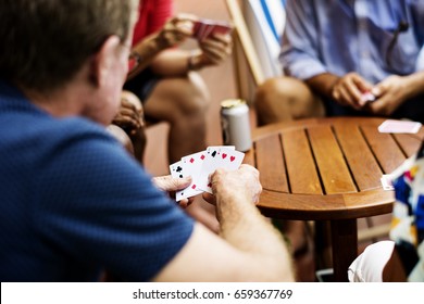 Rear View Of Man Playing Card Game With Friends