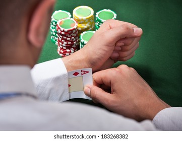 Rear view of man pulling ace card from sleeve in casino