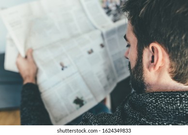 Rear View Of Man Reading Newspaper While Relaxing On Couch