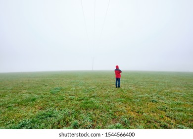 Rear view of man in red jacket standing on a green meadow and looking into a foggy nowhere landscape. Seen in October in Germany, Bavaria near Oedenberg. - Shutterstock ID 1544566400