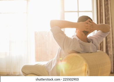 Rear view of man relaxing on chair at home