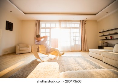 Rear View Of Man Relaxing On Modern Chair At Home