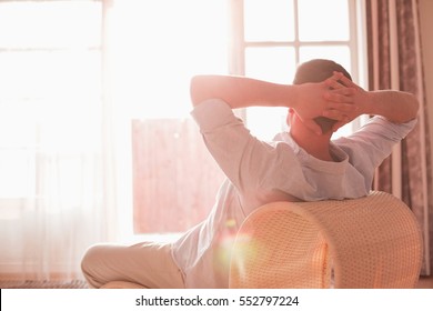 Rear View Of Man Relaxing On Chair At Home