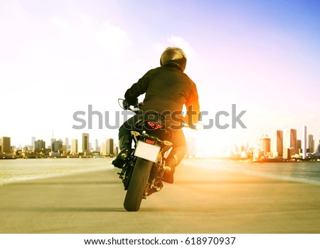 rear view of man riding motorcycle on urban traffic road for people leisure traveling theme