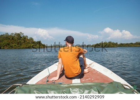 Rear view of man sitting on bow of boat during trip on lake, Sri Lanka
